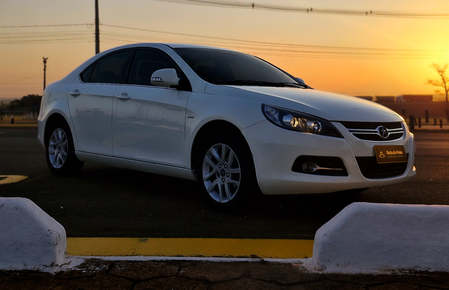 JAC J5 branco do Transfer do Peão em Barretos, visto de frente ao pôr do sol